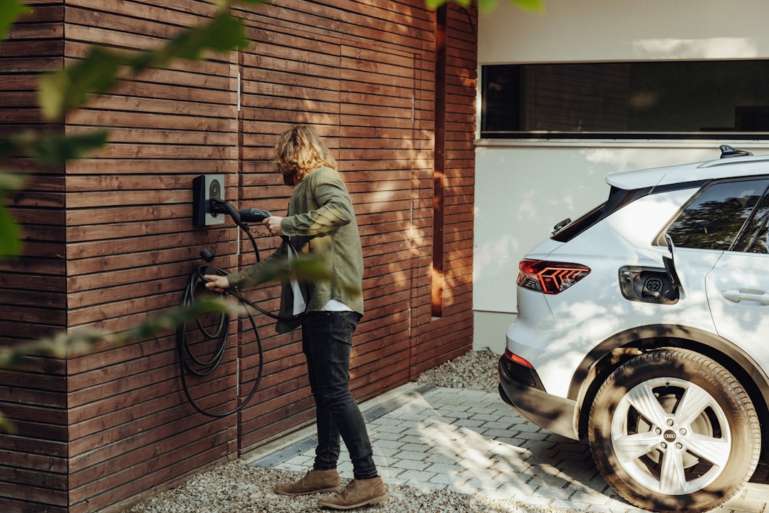 Modern home with an electric vehicle charging in the driveway at dusk.